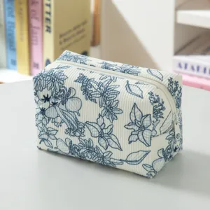 Nahaufnahme des Cordstoffs und des blauen Blumenmusters der tragbaren Reise-Kosmetiktasche
