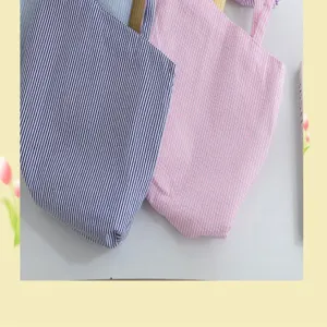 Close-up detail of navy and pink striped fabric tote bags showing soft seersucker texture