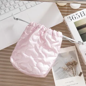 Primer plano de bolsa de PU rosa brillante con cordón y patrón de corazón acolchado.