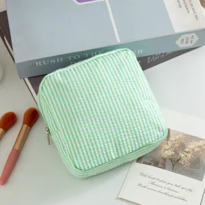 Detalle del neceser de seersucker a rayas verdes con una cremallera plateada metálica