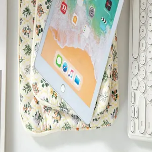 Macro view of a floral quilted tablet sleeve with iPad and white keyboard in scene.