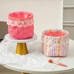 Quilted fabric storage baskets with lace trim and floral patterns on a white pedestal stand.