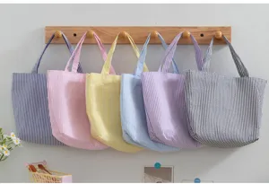 Detail view showing six colorful striped seersucker tote bags hanging on a rack.