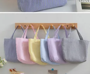Detail of colorful striped tote bags in various pastel colors hanging on a wooden rack
