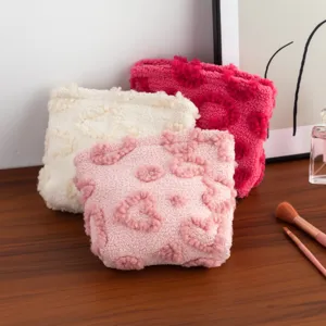 Detailed macro view of soft plush heart-patterned makeup pouches in three sweet colors