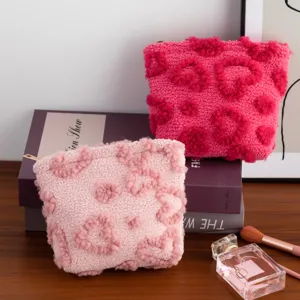 Detail of plush makeup bags with embossed heart patterns in pink and rose