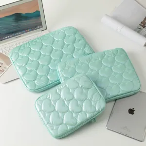 Vista detallada de tres fundas para portátil e iPad acolchadas con corazones en verde menta