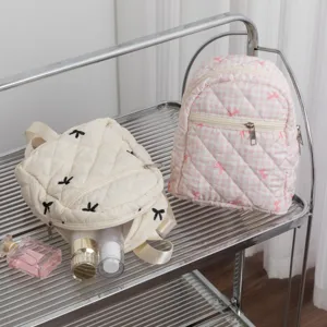Vista detallada de dos mini mochilas acolchadas con bordado de lazos en estantería