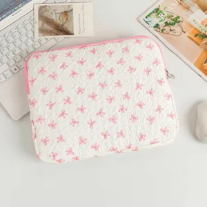 Detail der gesteppten Laptoptasche mit rosa Schleifenmuster auf weißem Schreibtisch