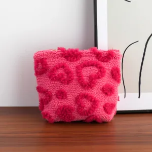 Detail view of a pink plush cosmetic bag with hot pink heart patterns and gold zipper.