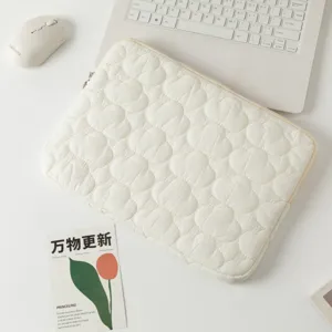 Dettaglio della morbida trama trapuntata a nuvola bianca su una custodia per laptop.