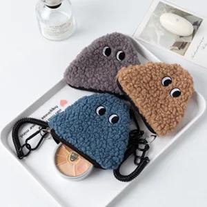 Macro detail of plush triangular coin purses featuring embroidered eyes and black zipper