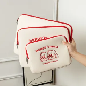 Trois housses d'ordinateur crème avec broderie lapin rouge et texte 'happy bunny'