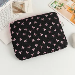 Nahaufnahme einer schwarzen Laptop-Tasche mit rosa Schleifenmuster auf einem weißen Schreibtisch