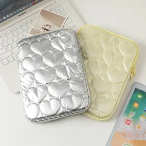 Funda acolchada de corazón para iPad y Macbook en un escritorio blanco.