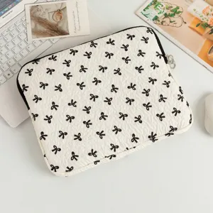 Detailansicht einer weiß gesteppten Laptoptasche mit schwarzem Schleifenmuster auf einem Schreibtisch