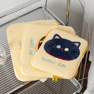 Detail van schattig kattenborduurwerk op pluche laptophoezen in het geel
