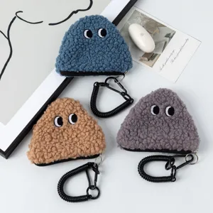Macro detail of plush triangle rice ball coin purses with cute eyes in three colors.