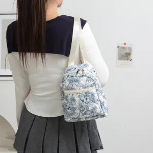 Vista trasera de una dulce mochila acolchada de flores usada por una niña en estilo escolar.