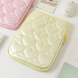 Primer plano detallado de una funda para portátil acolchada con corazones amarillo pastel.
