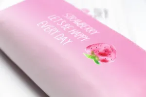 Nahaufnahme eines niedlichen Erdbeerdrucks auf einem rosafarbenen Leder-Mäppchen