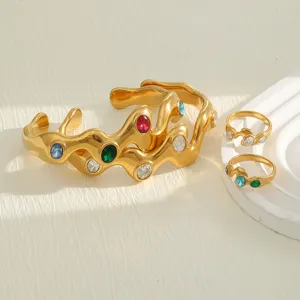 Detailed view of wavy 18K gold plated bangles and rings with colorful gemstones