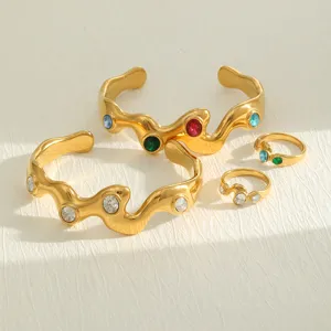 Macro view of vintage wavy gold-plated bracelets and rings set with colorful crystals.