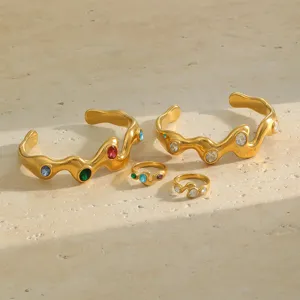 Detail view of wave-shaped 18K gold plated bracelets and rings with colored stones.