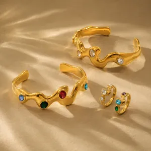 Close-up of vintage 18K gold plated stainless steel wavy bracelets and rings with crystals.
