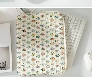 Detail view of floral quilted tablet sleeve liner bag with a white computer keyboard