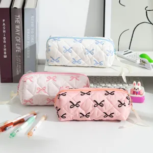 Close-up of three quilted bow-patterned large capacity pencil cases on a white desk