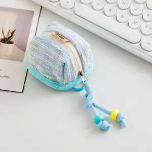 Detalle de la funda de tweed azul para auriculares con cremallera y cordón de cuentas