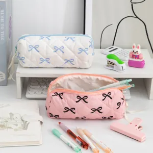 Large capacity quilted bowknot pencil cases in pink and white shown with desk stationery