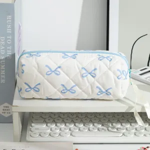 Macro detail of a white quilted pencil case with cute blue bow patterns for desk