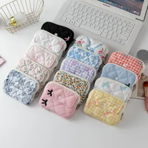 Minibolsas de almacenamiento acolchadas con flores y cuadros sobre escritorio blanco.