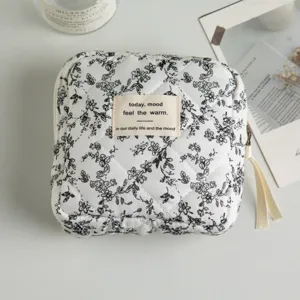 Close-up of a quilted floral cosmetic bag with a decorative fabric mood label in the center.