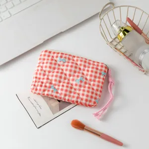 Primer plano de un neceser acolchado a cuadros rojos con pequeños lazos azules