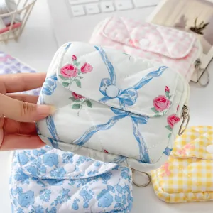Detalle de mini funda acolchada para auriculares con flores sostenida con varios patrones.