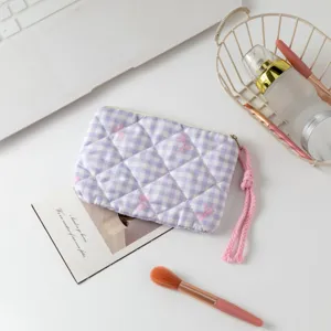 Vista superior de un neceser acolchado de cuadros morados con brochas de maquillaje