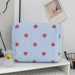 Dettaglio di una borsa cosmetica trapuntata a fragola a scacchi blu in una vanità