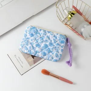 Neceser acolchado con flores azules y detalle de tirador de cremallera en morado