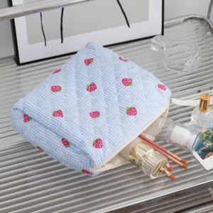 Dettaglio della borsa trucco trapuntata fragola blu con texture e motivo