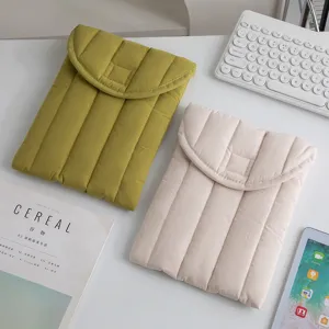 Primer plano de fundas acolchadas para tabletas en oliva y beige sobre un escritorio