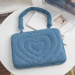 Herzförmiges Stickereidetail auf einer blauen Denim-Laptoptasche und Tablet-Hülle