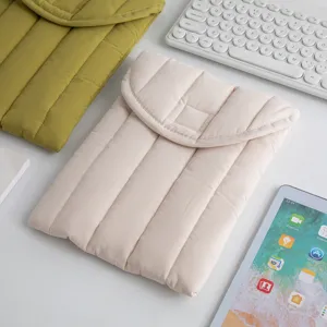 Primer plano de una funda acolchada crema para tableta en un escritorio blanco