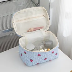 Borsa trucco trapuntata a quadretti con fragole aperta che mostra grande spazio