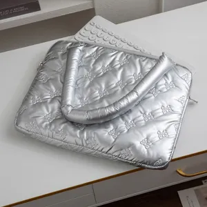 Vue détaillée du sac d'ordinateur argenté matelassé avec motifs de nœuds