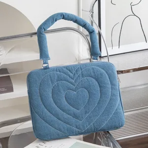 Detailansicht einer blauen Denim-Laptoptasche mit weißer Herzstickerei auf der Vorderseite