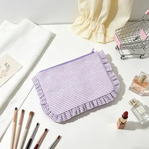 Close-up of seersucker striped cosmetic bag with ruffle edges and purple zipper