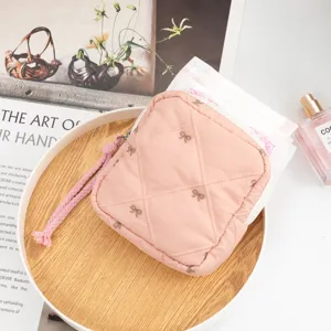 Pink quilted makeup bag with embroidered bows and wrist strap for cosmetic storage